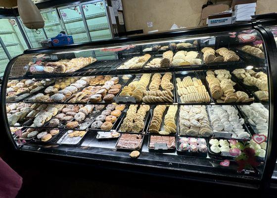 Display cases of danishes, cookies, donuts, and cupcakes