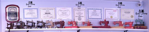 Miniature working sewing machines on display under Randy's certificates and awards...