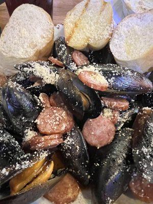 Mussels and sausage in white wine sauce with garlic and Cajun sauce served with bread