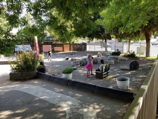 Calm outdoor play area where children can help take care of herbs and flowers.