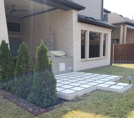 Nysa Travertine Paver with Black Star Granite Patio edge with lush planters edged in Colorado River Rock