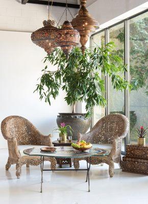 Hand-carved chairs, pietra dura table, and brass lighting.