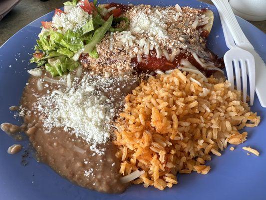 Chicken enchiladas with red sauce, rice, and refried beans