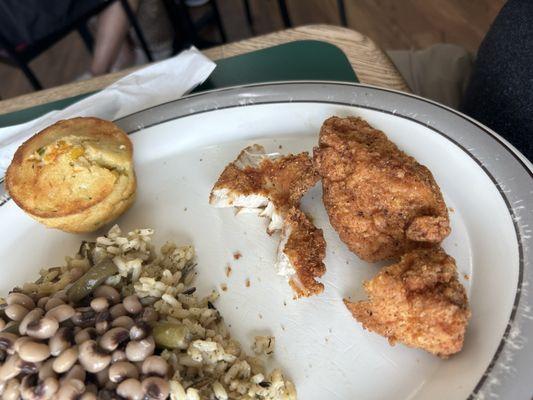 Three fried boneless tenders advertised as fried chicken breasts, wild rice, black eyed peas, and cornbread muffin.