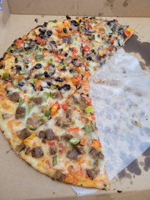 Pizza with one side with lamb and vegetables and the other half all vegetables.