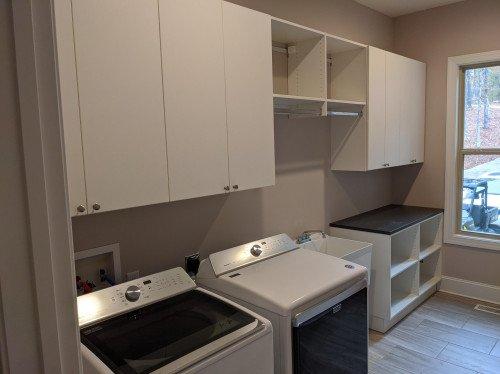 White and chrome laundry room storage with black folding counter.