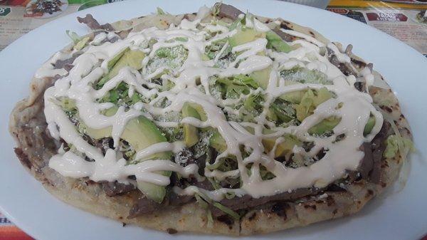 Huarache de Cecina: Long corn tortilla filled w/ refried beans, topped w/ salt-cured air-dried beef, lettuce, avocado, añejo cheese, & crema