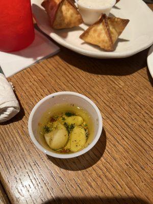 Dipping oil for $2 bread service.  Two raw chunks of garlic,  almost zero herbs, no flavor.  Buffalo chicken Rangoon in background.