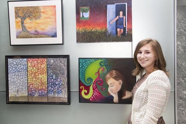 An advanced Usdan Center art student displays her work at the lobby gallery at 430 Park Avenue, NYC, last spring.