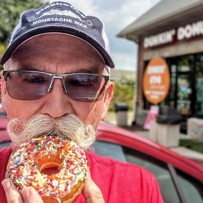 Lonny (@donutduster) enjoying a vanilla iced yeast donut with sprinkles.