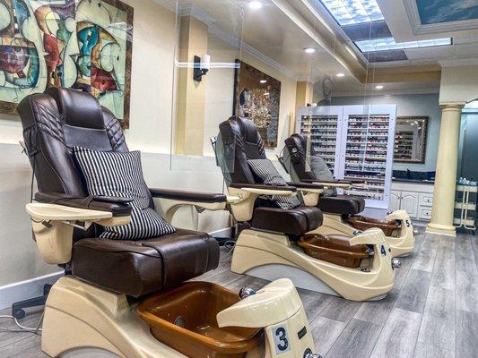 Pedicure chairs with plastic barriers between the nail technician and customer