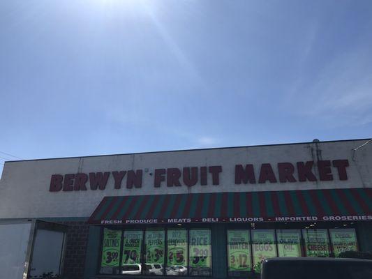 Exterior view of Berwyn Fruit Market with store signage in capital red letters that illuminate at night