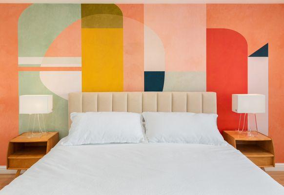 A midcentury modern style wall mural creates interest behind the padded headboard.