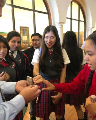 High School scholars touching St. Padre Pio's rosary at St. Thomas Aquinas College