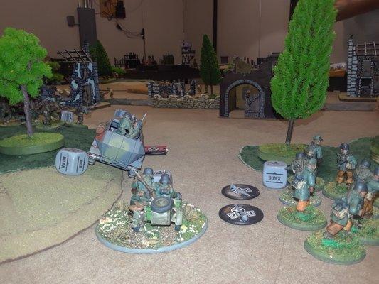 View from behind the Germans ; their command half-track, an MG-armed motorcycle and an infantry squad pushing through a gap in the woods.