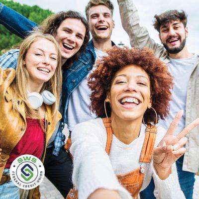 Five people taking selfie, smiling, logo.