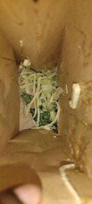 Spoiled sour shredded Jicama root vegetable spit out in a brown paper bag.