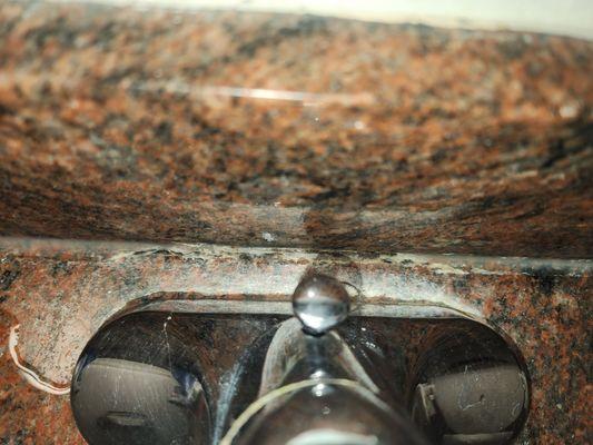 Residue behind the faucet in the bathroom.