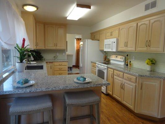 New granite countertops, glass tile backsplash, microwave, and stainless steel sink and faucet. Fresh paint.