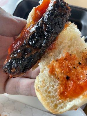 The second Charcoal burned hot dog drenched in ketchup