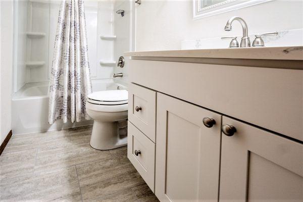 Complete bathroom remodels with new tub enclosure, lighting, vanity, countertop, and tile floor.