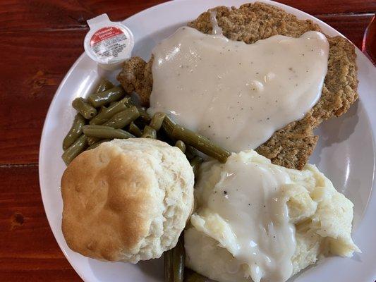 Chicken fried steak, mashed potatoes with gravy, green beans, and a homemade biscuit