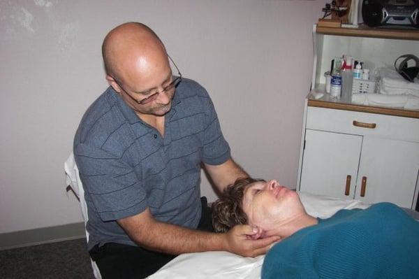 Alan providing client with massage therapy on her neck.