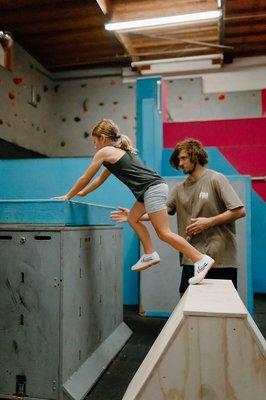 Coach sam spotting a leap during one of our weekly kids parkour classes in Murrieta