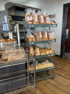 Whole loaves of fresh baked bread. Baguettes are at the front on top of the counter.