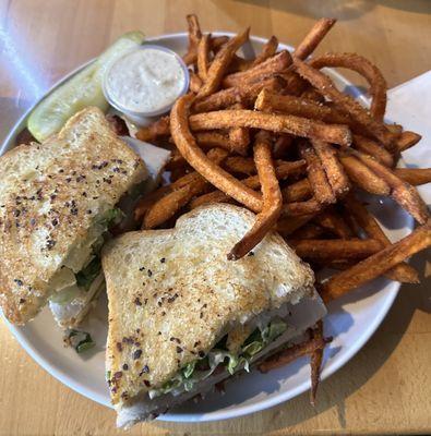 Club sandwich on white bread with sweet potato fries.