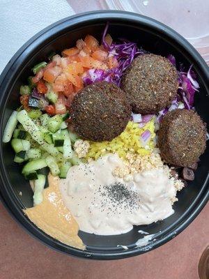 The bowl with rice, red pepper hummus, falafel, tomatoes, cucumber, cabbage, red onion, olives, spicy feta w/spicy taziki sauce.