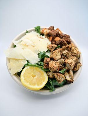 A bed of kale with shaved parmesan cheese, croutons, FG signature jerk chicken and jerk caesar dressing