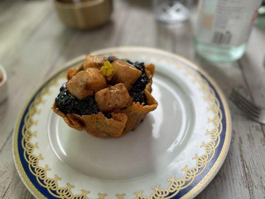 Scallops over black squid ink risotto in an edible Parmesan bowl