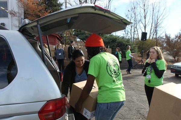 Volunteers help load Thanksgiving food boxes for families in need.