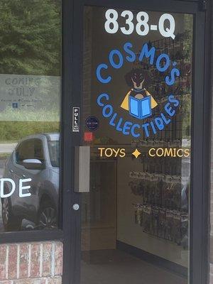 Door showing store is opening soon.  Logo with dog reading comic and words, Cosmo's Collectibles: Toys and Comics.