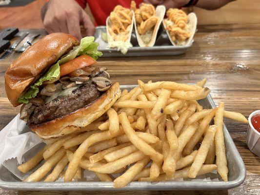 Mushroom Swiss burger with fish tacos in the background