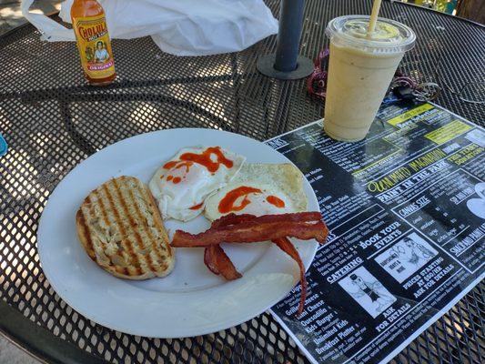 Rise and shine with two over medium eggs, bacon, toast, and a fruit smoothie.