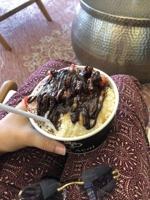 Acai/coconut power bowl with bananas, granola, strawberries, coconut, and cacao drizzle.