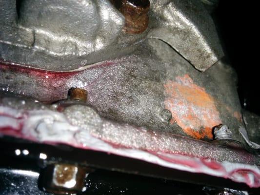 Large hammer mark and crack on transmission above the left bolt, caused by a midas technician not using the proper tools