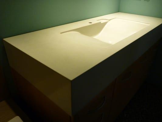 Concrete vanity with integral wave sink and soap dish.