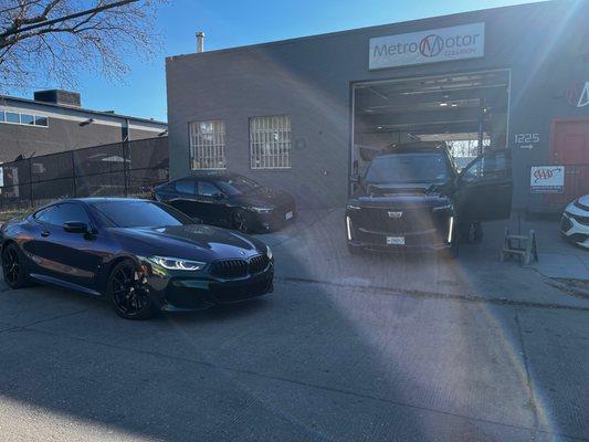 BMW and Cadillac parked in front of Metro Motor auto body shop and collision repair center