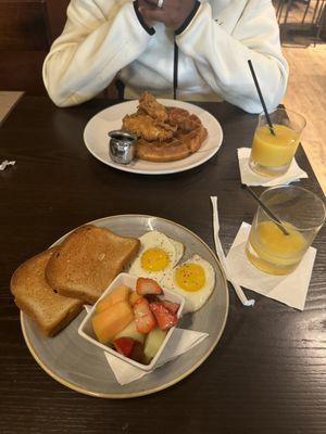 chicken and waffles and eggs and toast with fruit salad