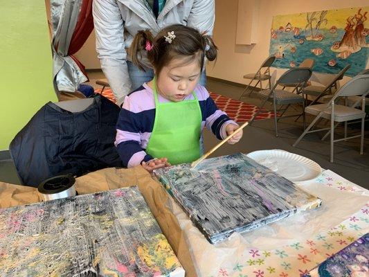 Little Hands' youngest apprentice, helping to gloss a group of drip-pour paintings.