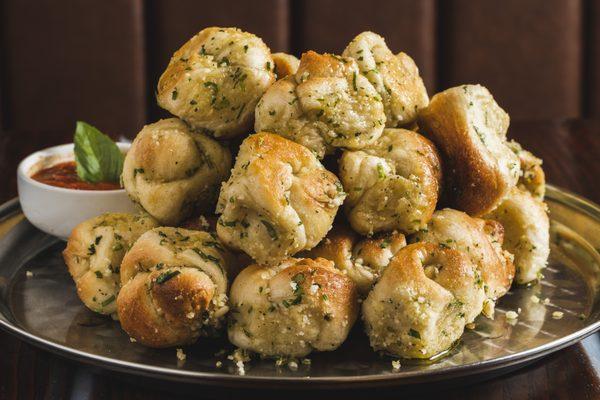 Garlic knots with a side of complimentary marinara sauce.