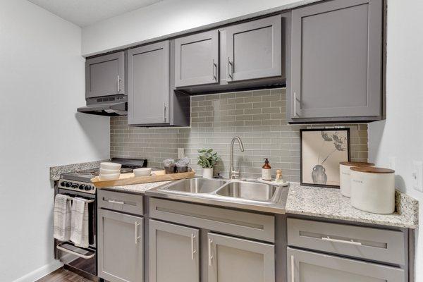 Kitchen with designer grey cabinetry and tile backsplash.