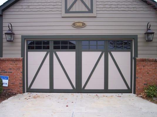 Insulated carriage-style garage door with custom trim color and glazed window glass.