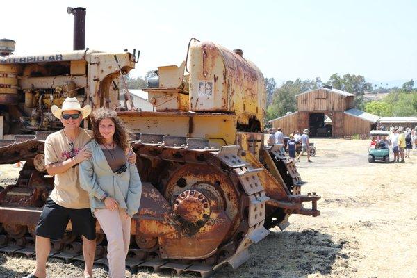 Jason with a family member posing in front of a big tractor near our commercial property.