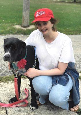 A woman hugging her foster dog, Macarena, in the park. Mac is a sweet silly pibble mix available for adoption through One Tail At A Time.