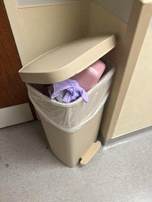 Soiled bed pan and other hazardous materials overflowing from garbage.