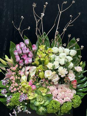 White roses pink roses tossed in a beautiful pastel palette combined with branches and orchids